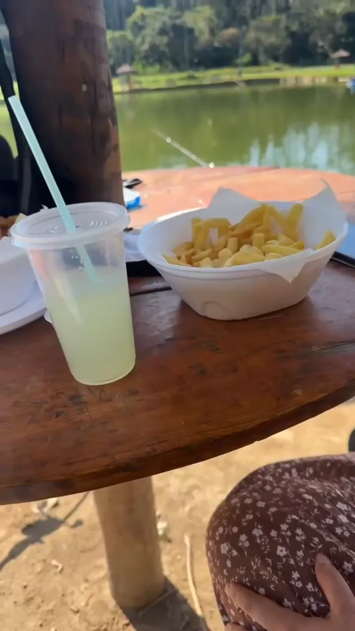 Mesa de madeira com porção e limonada, com o lago ao fundo