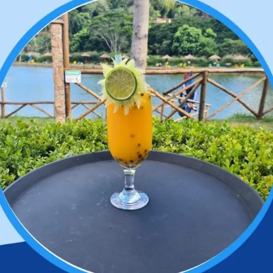 Drink de maracujá numa taça, com o lago ao fundo